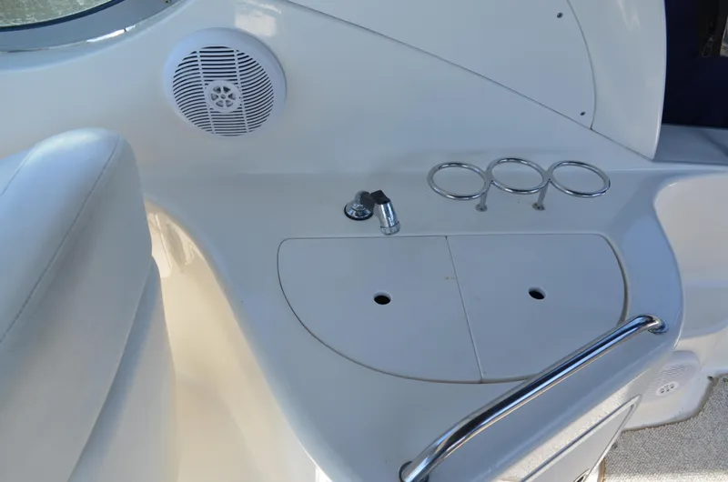 Slide: The Image of 2004 Sea Ray 280 Sundancer cockpit with speaker, cup holders, and storage compartment. - 11