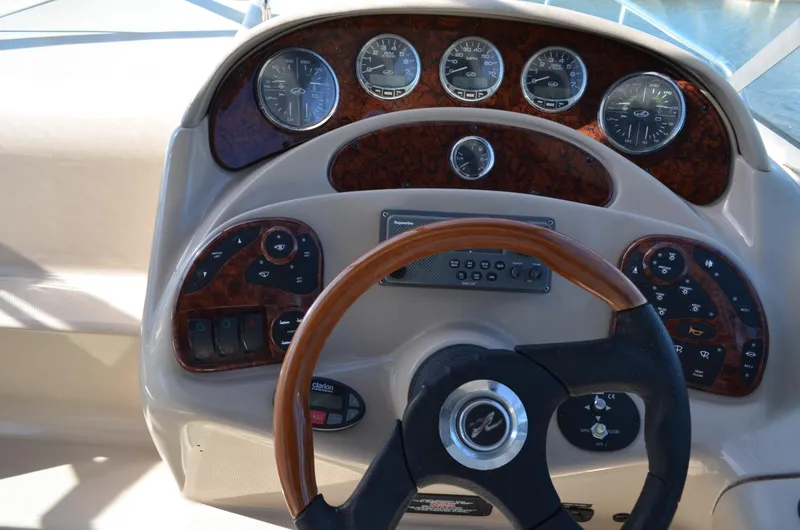 Slide: The Image of Dashboard of a 2004 Sea Ray 280 Sundancer boat with wood accents and steering wheel. - 21
