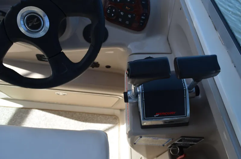 Slide: The Image of 2004 Sea Ray 280 Sundancer helm with steering wheel and Mercury throttle controls. - 23