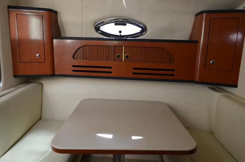 Slide: The Image of 2004 Sea Ray 280 Sundancer cabin interior with wooden cabinets and dining table. - 30