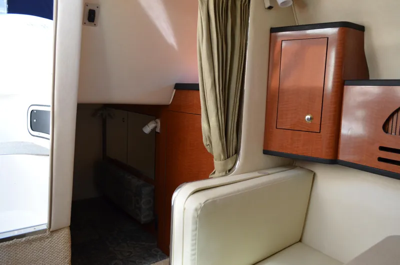 Slide: The Image of Interior of 2004 Sea Ray 280 Sundancer, featuring wood cabinetry and beige seating. - 31