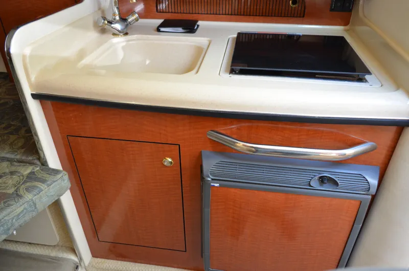 Slide: The Image of 2004 Sea Ray 280 Sundancer galley with sink, stove, and compact fridge. - 38