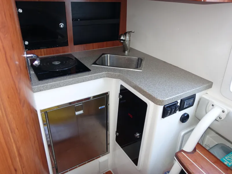 Slide: The Image of 2016 Regulator 41 boat kitchenette with sink, stove, and storage cabinets. - 24