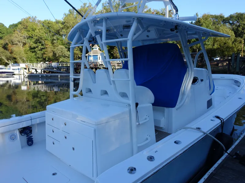 Slide: The Image of 2016 Regulator 41 boat with white deck and blue seating, docked by a scenic waterfront. - 4