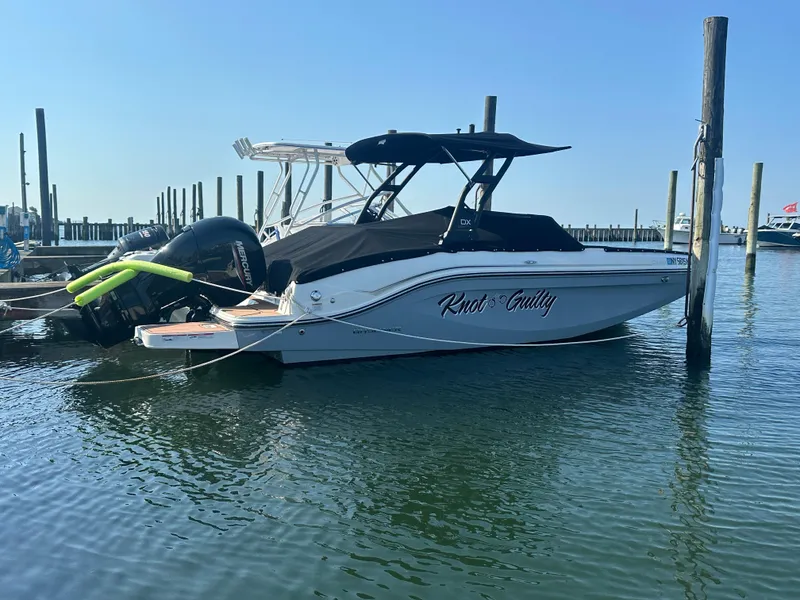 Slide: The Image of 2022 Bayliner DX 2000 boat named "Knot Guilty" docked in a marina. - 0