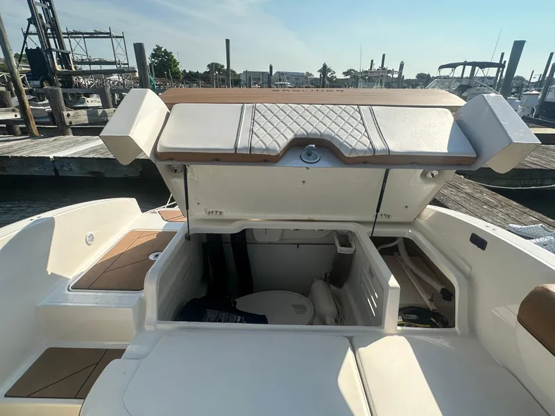 Slide: The Image of 2022 Bayliner DX 2000 boat interior with open storage compartment at marina. - 13