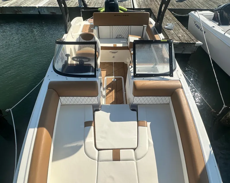 Slide: The Image of 2022 Bayliner DX 2000 boat interior with tan and white seating, docked at marina. - 2