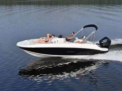 Slide: The Image of 2025 Stingray 212SC boat cruising on a calm lake with passengers. - 1