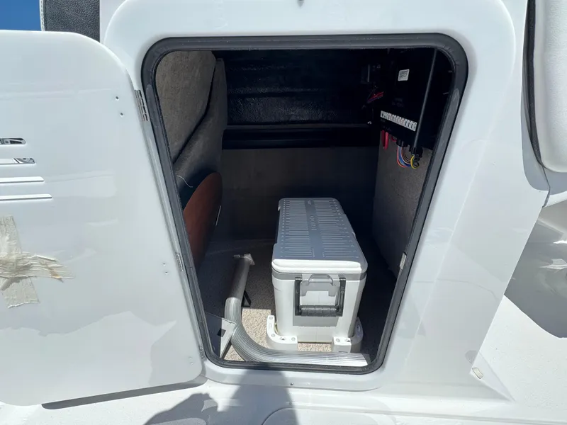 Slide: The Image of Storage compartment of 2025 Stingray 231DC boat, featuring organized wiring and a portable cooler. - 10