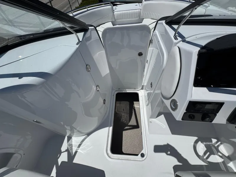 Slide: The Image of 2025 Stingray 231DC boat interior with open storage compartment and sleek white design. - 11