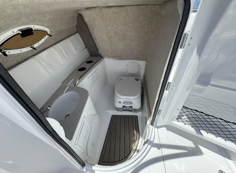 Slide: The Image of 2025 Stingray 231DC boat interior with compact bathroom, featuring a toilet and sink. - 14