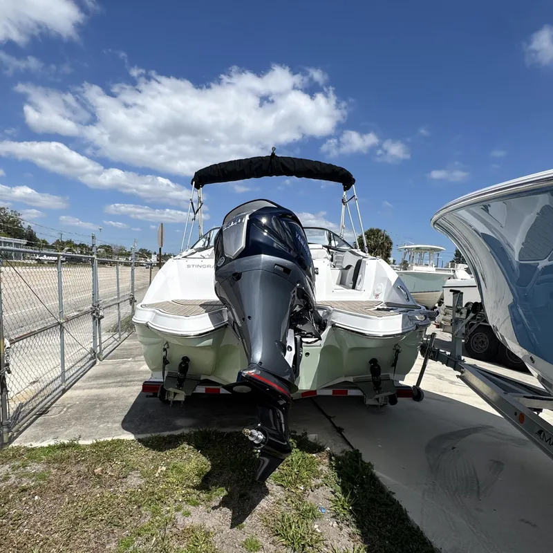 Slide: The Image of 2025 Stingray 231DC boat with outboard motor, parked under a clear blue sky. - 2