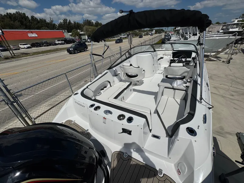 Slide: The Image of 2025 Stingray 231DC boat with spacious seating and sleek design, docked under sunny skies. - 4