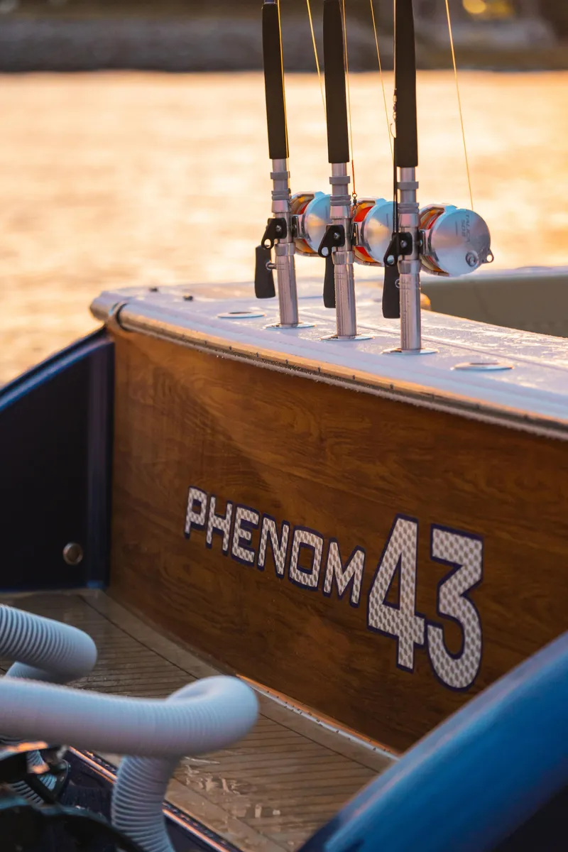 Slide: The Image of Phenom 43 boat, 2025 model, with fishing rods on deck at sunset. - 9