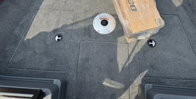 Slide: The Image of 2025 Tracker Pro Guide V-175 WT boat interior with carpeted floor and packaged equipment. - 11