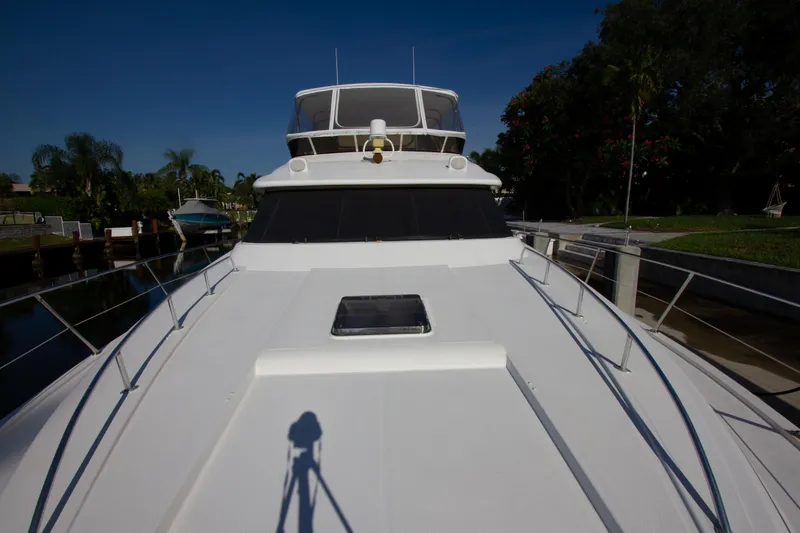 Slide: The Image of Johnson 70 Motor Yacht 1999, front deck view, docked near lush greenery. - 13