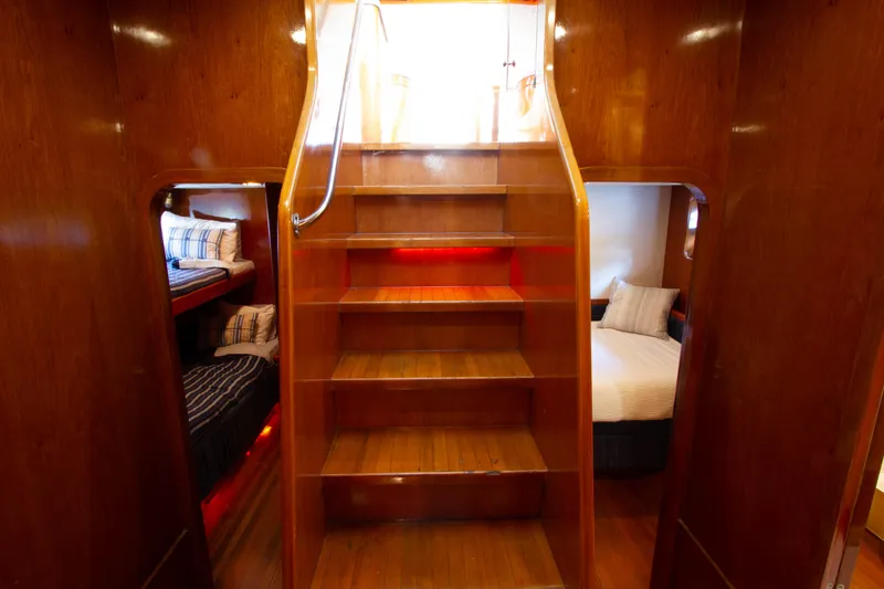 Slide: The Image of Luxurious wooden staircase on 1999 Johnson 70 Motor Yacht with cozy cabin beds. - 24