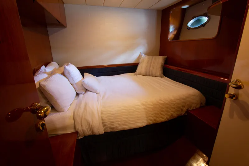Slide: The Image of Cozy bedroom interior on 1999 Johnson 70 Motor Yacht with plush bedding and wooden accents. - 25