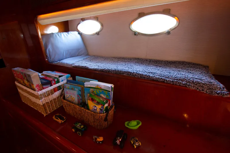 Slide: The Image of Cozy cabin with books and toys on a 1999 Johnson 70 Motor Yacht. - 30