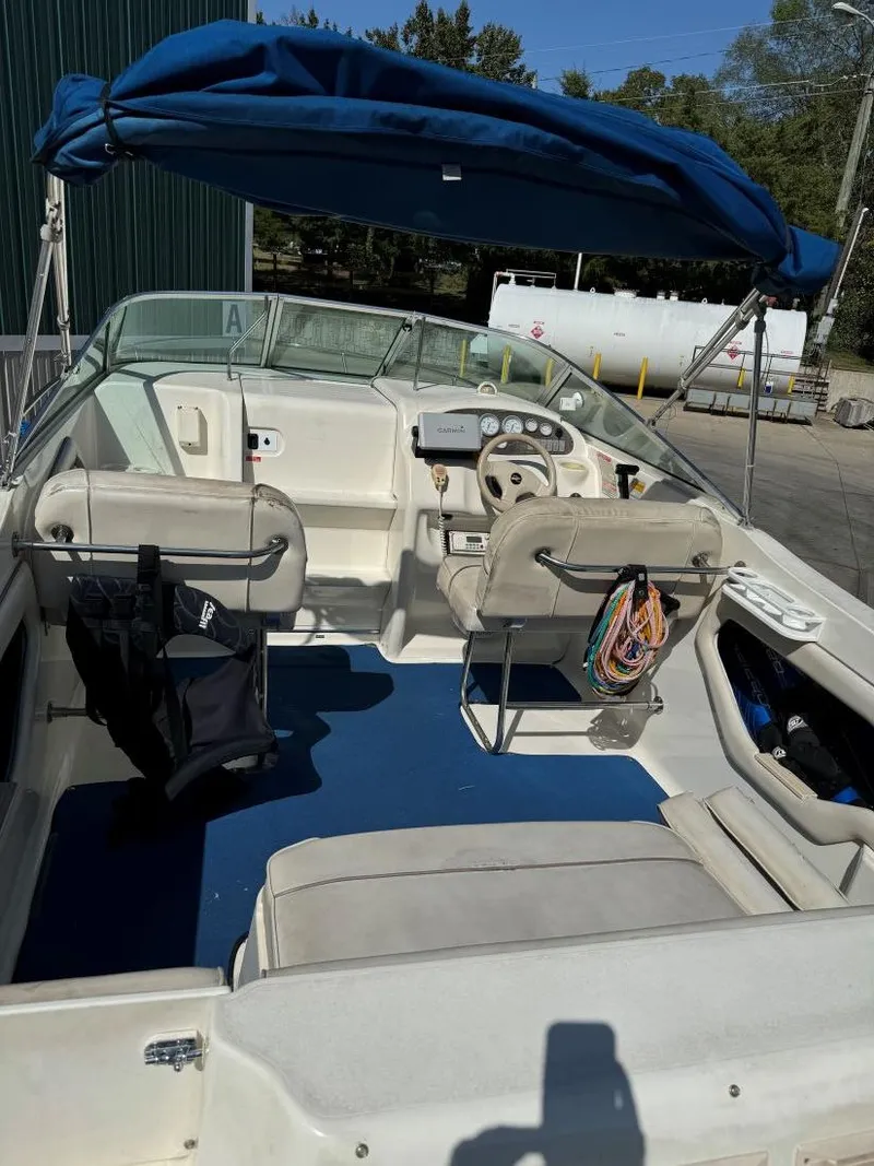 Slide: The Image of 1996 Sea Ray 215 Express Cruiser with blue canopy and spacious seating. - 13