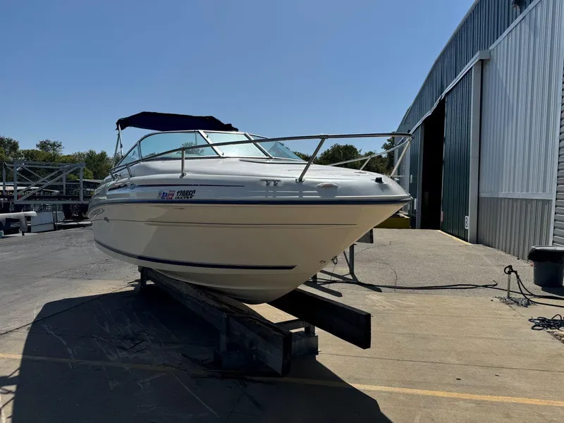 Slide: The Image of 1996 Sea Ray 215 Express Cruiser boat on a trailer outside a warehouse. - 5