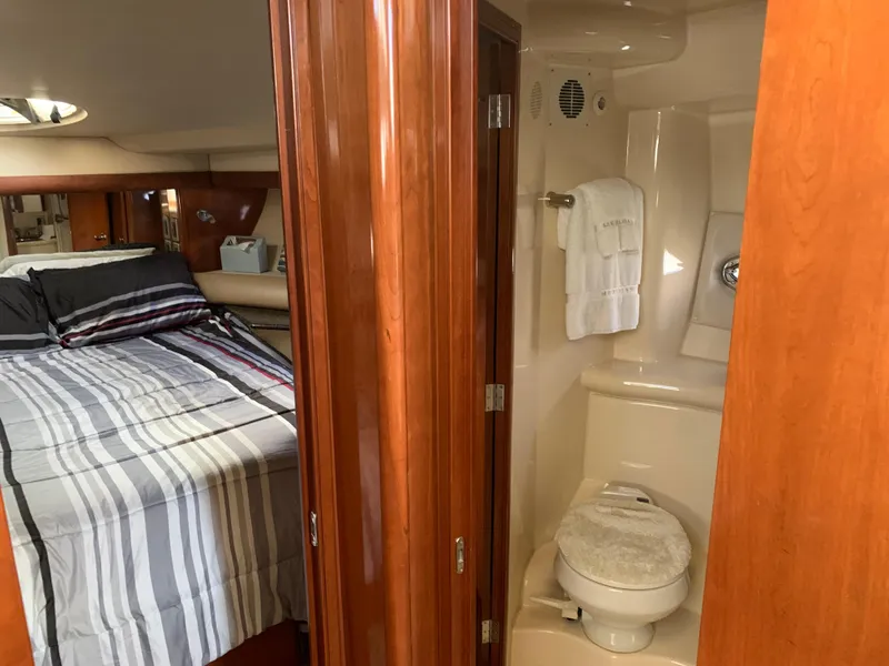Slide: The Image of 2006 Meridian 459 Motoryacht interior with bedroom and bathroom, featuring wood paneling and striped bedding. - 11