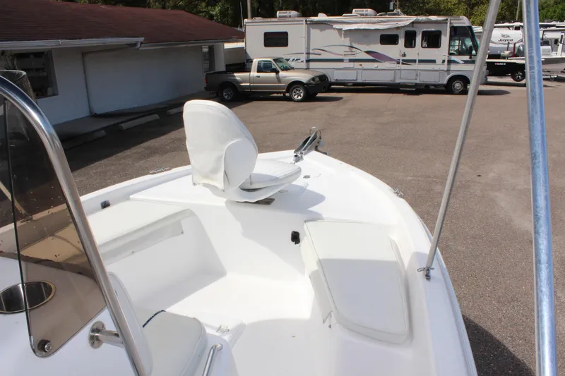 Slide: The Image of 2002 Cobia 191 Bay boat with white seating, parked near RV and truck. - 15
