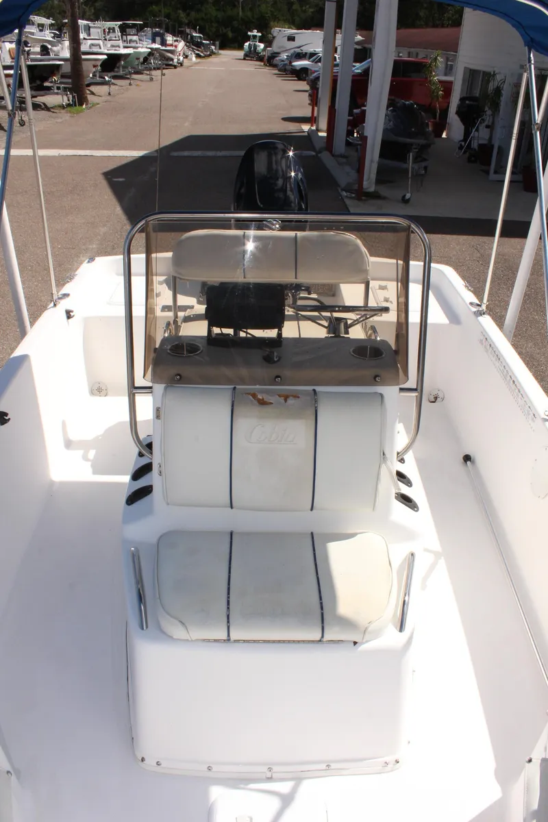 Slide: The Image of 2002 Cobia 191 Bay boat interior with seating and console, docked at marina. - 24