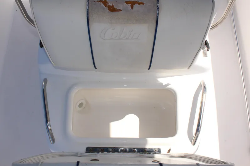 Slide: The Image of 2002 Cobia 191 Bay boat seat and storage compartment, showing wear and tear. - 25