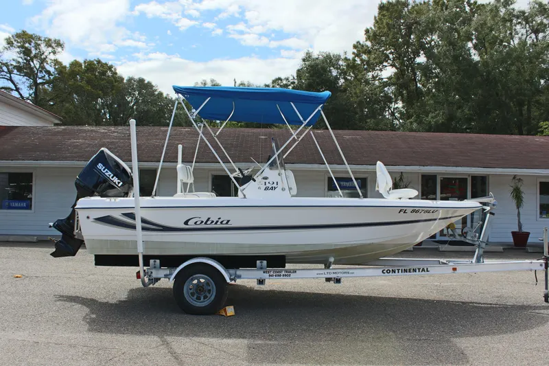 Slide: The Image of 2002 Cobia 191 Bay boat on trailer with blue canopy and Suzuki outboard motor. - 3