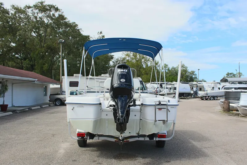 Slide: The Image of 2002 Cobia 191 Bay boat with outboard motor and blue canopy in a parking lot. - 6