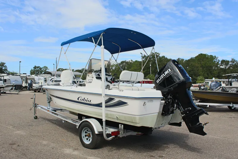Slide: The Image of 2002 Cobia 191 Bay boat with Suzuki outboard motor on trailer, blue canopy. - 7