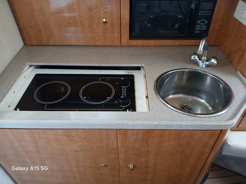 Slide: The Image of 2002 Regal Commodore 3060 boat kitchen with stove, sink, and microwave. - 23