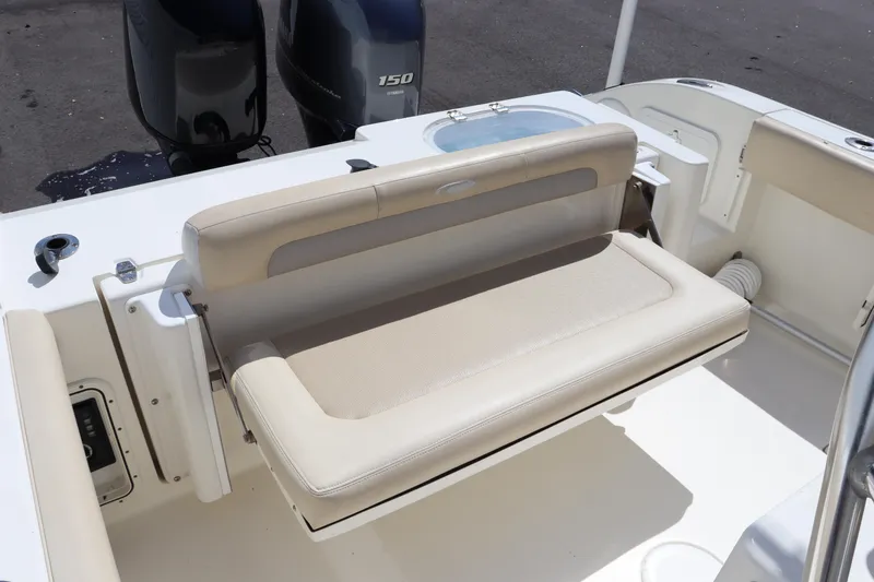 Slide: The Image of 2012 Cobia 256 CC boat with foldable rear bench seat and dual outboard motors. - 20