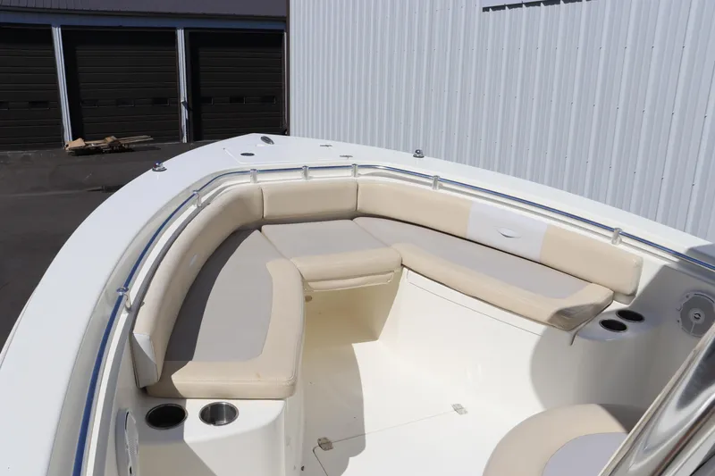 Slide: The Image of 2012 Cobia 256 CC boat with beige seating and cup holders, docked near storage units. - 23