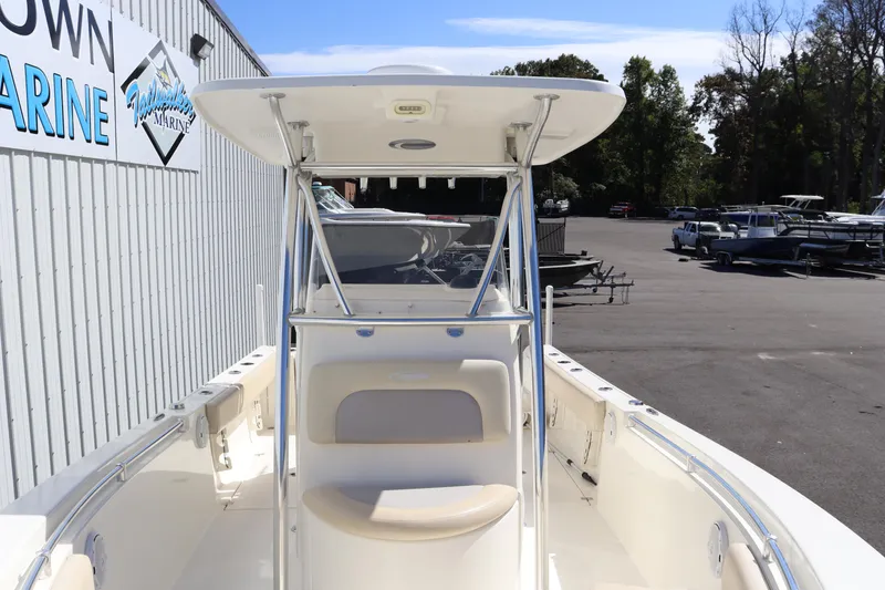Slide: The Image of 2012 Cobia 256 CC boat at a marina, front view with seating and T-top. - 26