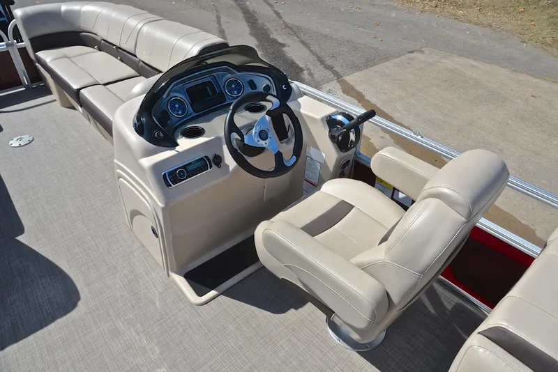 Slide: The Image of 2018 Sun Tracker Party Barge 24 DLX interior with beige seating and steering console. - 24