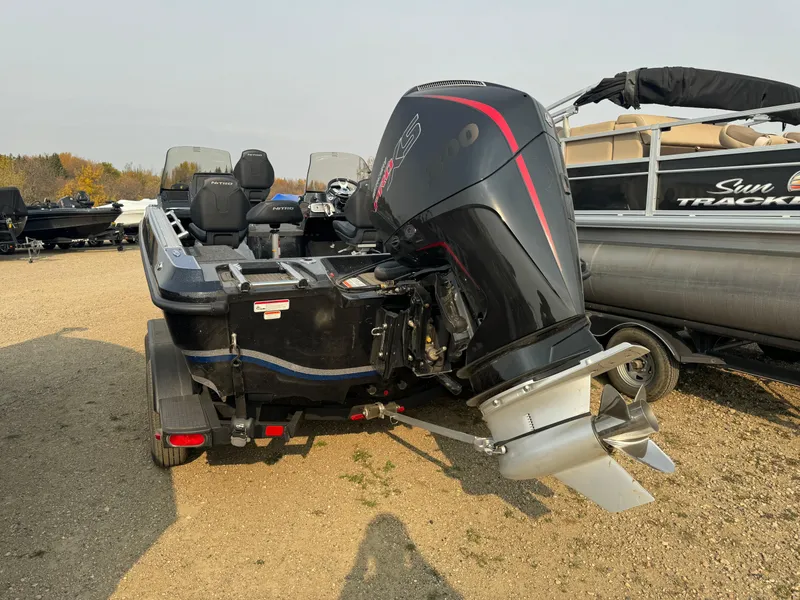 Slide: The Image of 2024 Nitro ZV20 boat with powerful outboard motor, parked on gravel. - 5