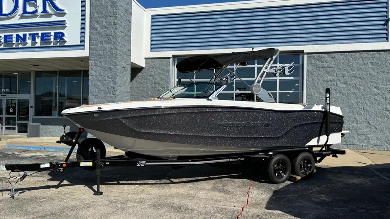Slide: The Image of 2025 MasterCraft XT24 boat on trailer outside dealership. - 0