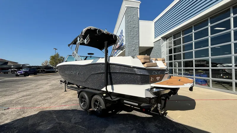 Slide: The Image of 2025 MasterCraft XT24 boat on trailer outside dealership, sunny day. - 1