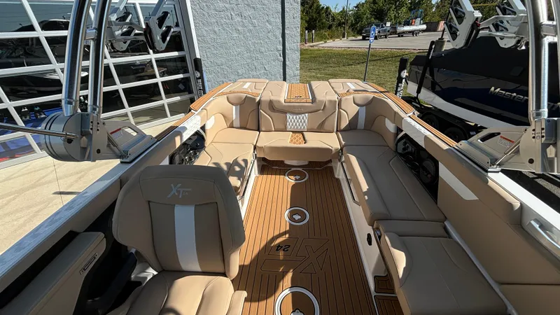 Slide: The Image of 2025 MasterCraft XT24 boat interior with beige seating and wood flooring. - 18
