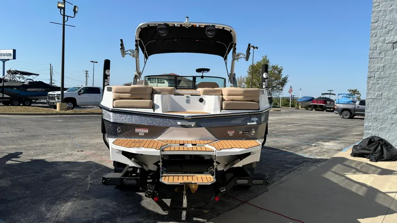 Slide: The Image of 2025 MasterCraft XT24 boat with teak swim platform, parked outdoors. - 2
