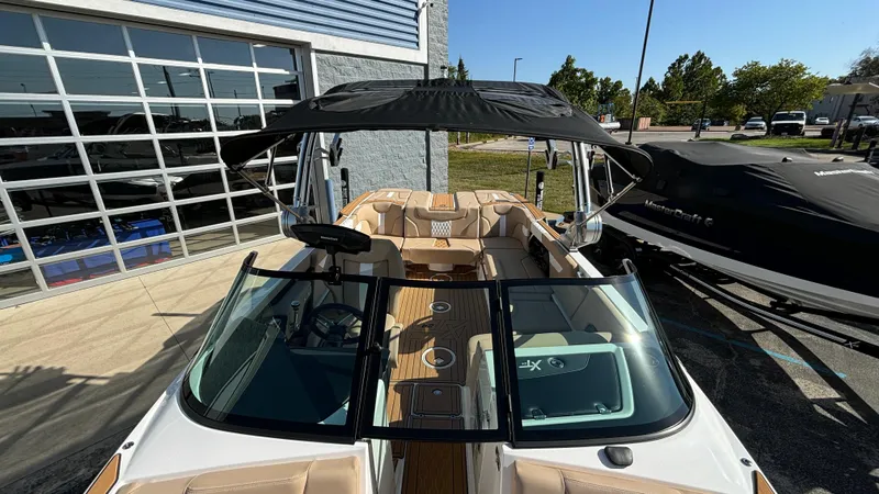 Slide: The Image of 2025 MasterCraft XT24 boat with black canopy and beige interior, parked outdoors. - 21