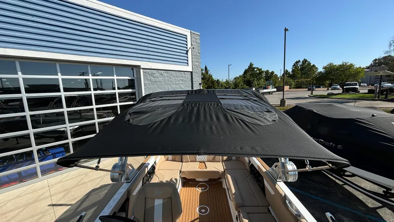 Slide: The Image of 2025 MasterCraft XT24 boat with black canopy, parked outdoors. - 22