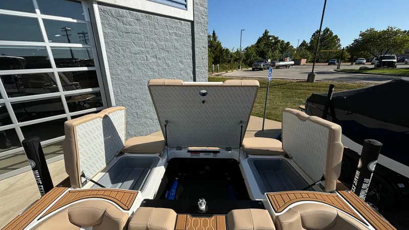 Slide: The Image of 2025 MasterCraft XT24 boat interior with open storage compartments, parked outdoors. - 28