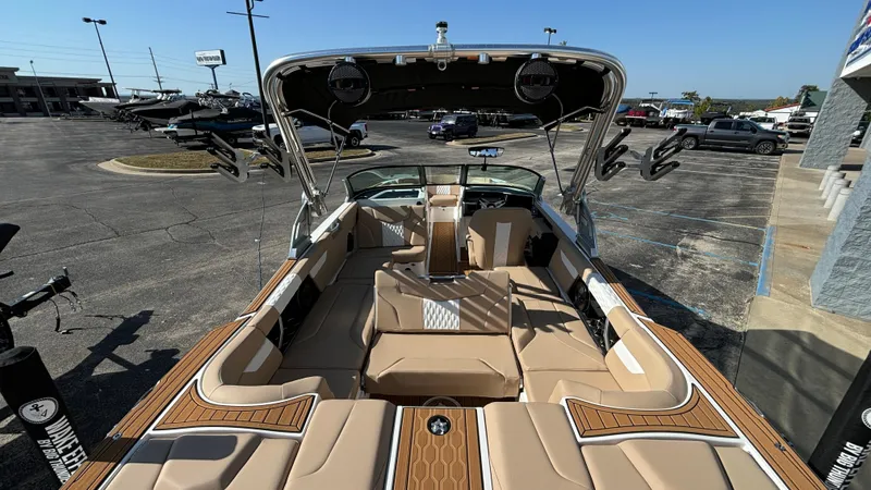 Slide: The Image of 2025 MasterCraft XT24 boat with luxurious seating and sleek design in a parking lot. - 31