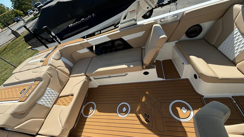 Slide: The Image of 2025 MasterCraft XT24 boat interior with tan seating and teak flooring. - 8