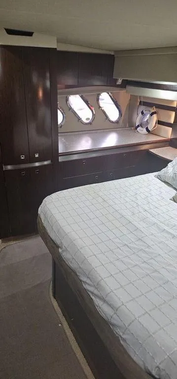 Slide: The Image of Luxurious 2011 Cruisers Yachts 540 bedroom with elegant wood cabinetry and porthole windows. - 29