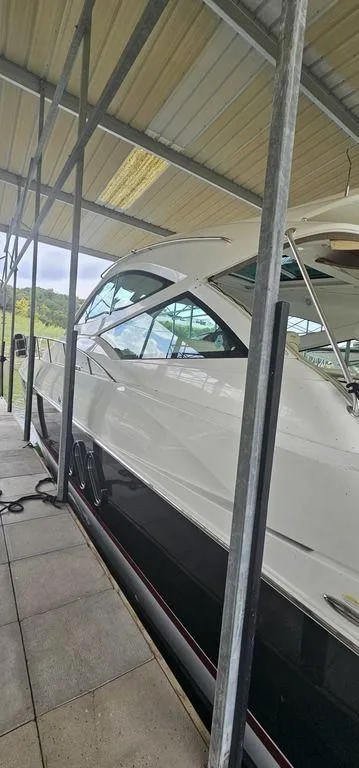 Slide: The Image of 2011 Cruisers Yachts 540 in dock, sleek white exterior under covered shelter. - 3