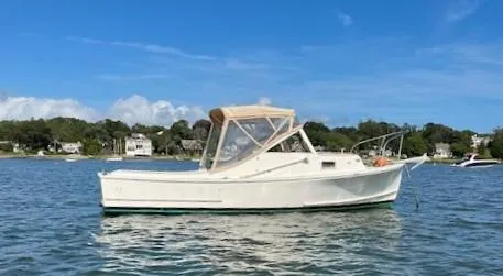 The Image of 1984 SISU Cuddy boat on calm water under clear blue sky. - 0